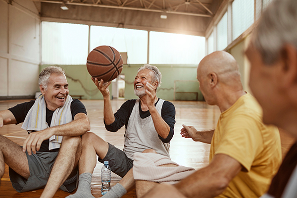 group of senior men sitting on gymnasium floor after playing basketball
